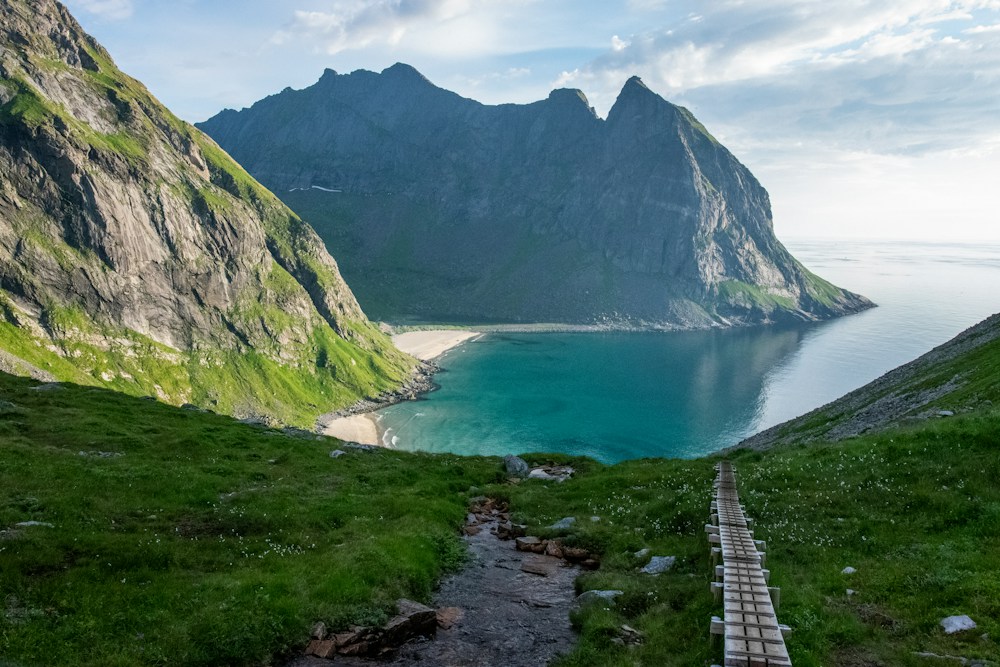 Ein Weg durch grüne Wiesen zum Meer zwischen hohen Bergen.